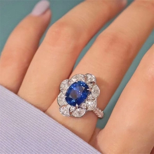 Elegant royal blue sapphire cocktail ring with diamond halo in a silver floral setting