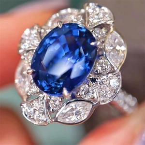 Elegant oval royal blue sapphire ring with a sparkling floral diamond cluster halo
