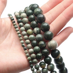 Perle rotonde in diaspro verde naturale di varie dimensioni mostrate sulla mano