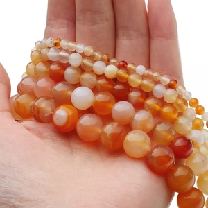 Dettaglio di perle di agata rosa naturale tenute in mano con trama a strisce e finitura lucida