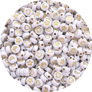 Detailed macro view of white acrylic beads with golden star and moon symbols for DIY jewelry