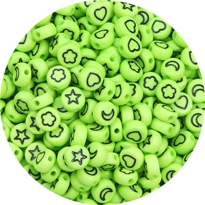 Macro detail of round light green acrylic beads with black star and moon symbols