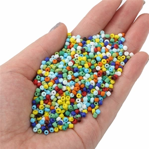 Mix di perline opache da 2mm per gioielli fai-da-te tenute in mano su sfondo bianco