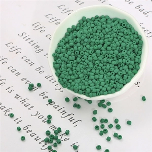 Dettaglio macro di perline di vetro verde scuro opaco per bigiotteria fai-da-te in ciotola
