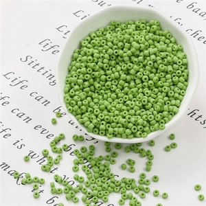 Dettaglio di perline verde matcha opaco per gioielli fai-da-te in una ciotola di ceramica