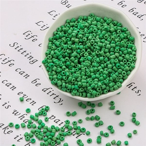 Macro di perline di vetro verde opaco in una ciotola bianca per gioielli fai-da-te
