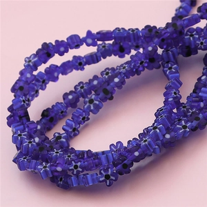 Vue macro de perles en verre bleu foncé translucide en forme de fleur pour bijoux DIY