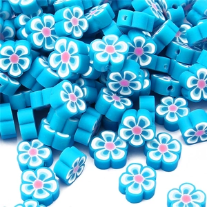 Vue détaillée de perles fleurs en pâte polymère bleu et rose pour la création de bijoux