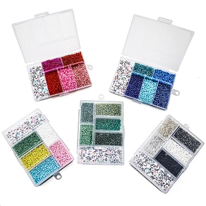 Draufsicht auf ein 5-Boxen-Set mit bunten Glasperlen und Alphabet-Anhängern für DIY-Schmuck