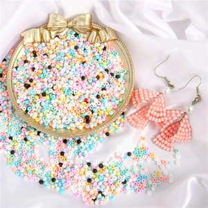 Close-up of 3mm colorful matte beads with handmade pink bow earrings on white silk