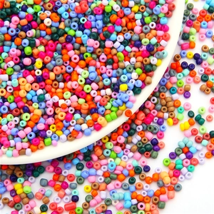Mix of colorful round glass seed beads in a white ceramic dish for DIY jewelry making