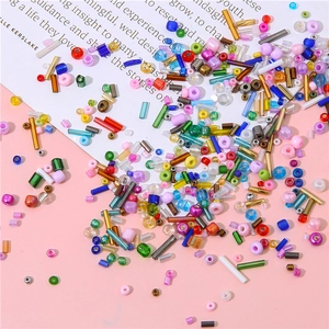 Macro shot of colorful mixed glass beads for DIY jewelry on pink and white backdrop