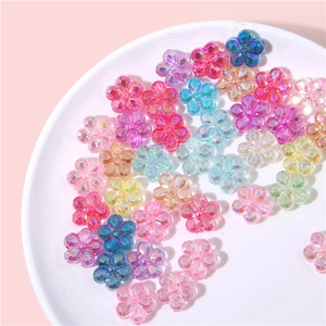 Mix of colorful iridescent acrylic flower beads for DIY jewelry making in a white ceramic dish