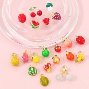 Assorted colorful enamel fruit pendants for DIY jewelry making on pink background