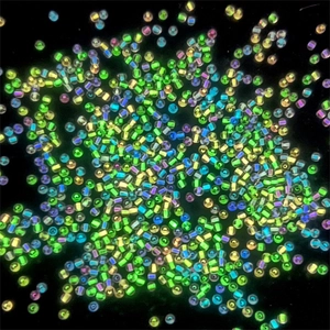 Macro shot of 2mm glow-in-the-dark glass seed beads in vibrant neon colors for DIY jewelry