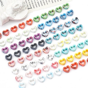 Macro detail of heart-shaped hollow ceramic beads with colorful marble ink patterns