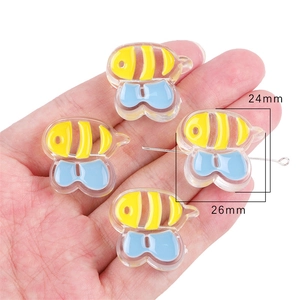Detailed close-up of acrylic bee beads with size measurements held in palm