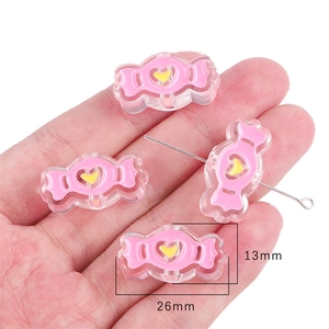 Detailed view of pink candy-shaped acrylic beads with yellow heart for DIY crafts