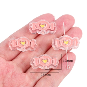Close-up of pink candy-shaped resin beads with yellow hearts for DIY jewelry making