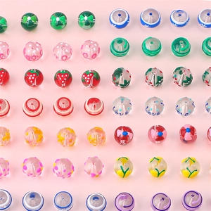 Macro shot of assorted colorful hand-painted glass beads with strawberry and bow patterns