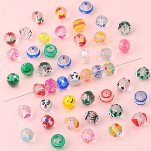 Macro detail of colorful DIY glass beads with panda and strawberry patterns for jewelry