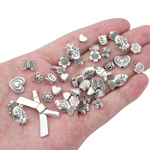 Antique silver DIY jewelry beads set featuring butterfly heart and leaf shapes in palm