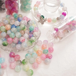 Macro-opname van kleurrijke glazen kralen met crackle-effect en vlinderhanger voor DIY-sieraden