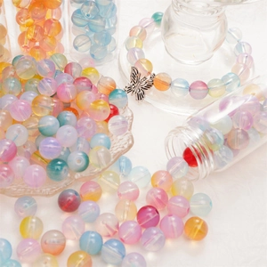 Macro-opname van kleurrijke glazen kralen voor DIY-sieraden met een zilveren vlinderhanger