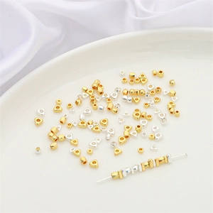 Golden and silver geometric metal spacer beads for DIY jewelry making displayed on a plate