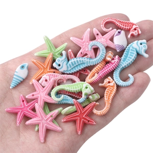 Macro view of colorful acrylic ocean animal beads held in hand for size comparison