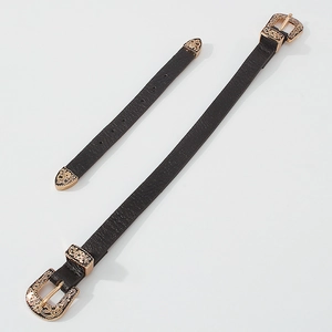 Dettaglio del choker in pelle nera con fibbie in bronzo incise a motivi floreali barocchi