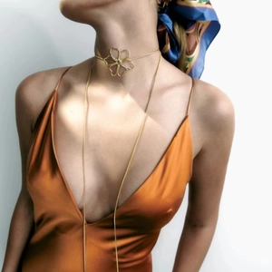 Detailed view of hollow gold flower choker necklace on a model wearing an orange dress