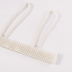 Primer plano de elegantes perlas blancas tejidas en una cadena corporal artesanal