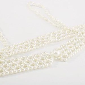 Gros plan d'une chaîne de corps en perles blanches tissées avec des perles brillantes