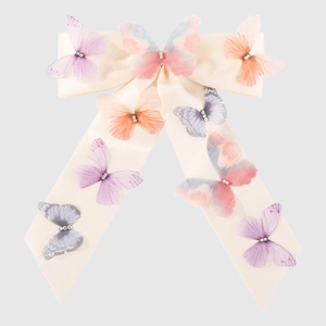Detailed view of cream satin bow hair clip adorned with colorful 3D butterflies and crystals