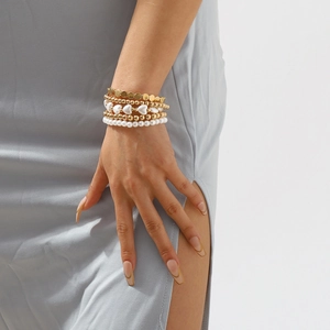 Detalle de un conjunto de pulseras de perlas y cuentas doradas en la muñeca