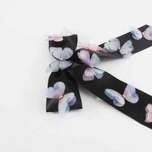 Detail of black satin hair ribbon with gradient butterfly wings and diamond embellishments