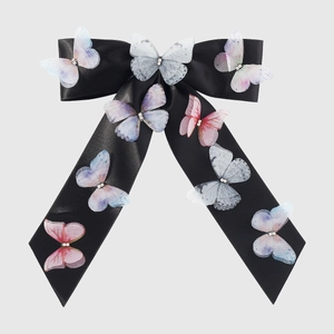 Detail of black satin bow hair clip with colorful crystal butterfly accents