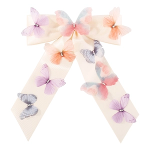 Close-up of a cream satin bow hair clip with colorful organza butterflies and rhinestones