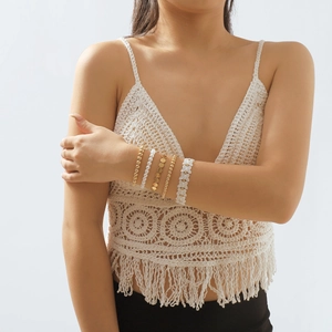 Detalle de un conjunto de cinco pulseras de cuentas doradas y perlas con encaje de mariposa