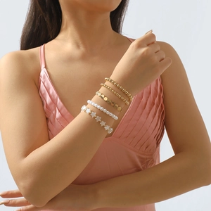 Detalle de pulseras de cuentas doradas en capas y dije de estrella blanca en la muñeca