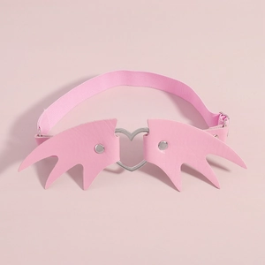 Détail de la chaîne de jambe en cuir rose avec cœur évidé et ailes de démon