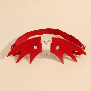 Détail d'une jarretière en cuir rouge avec ailes de chauve-souris et anneau en cœur