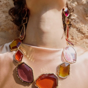 Detailed view of chunky resin geometric necklace and earrings on a model in silk clothing