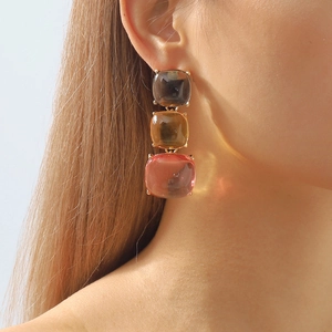 Détail de boucles d'oreilles géométriques bohèmes avec trois gemmes colorées en résine