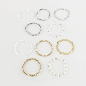 Detalle de plano de conjunto de 10 pulseras de perlas y cuentas metálicas sobre blanco