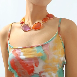 Macro shot of colorful geometric resin gemstones on a gold necklace worn by a model