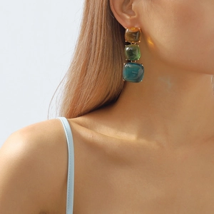 Détail de boucles d'oreilles pendantes en résine à trois carrés géométriques colorés