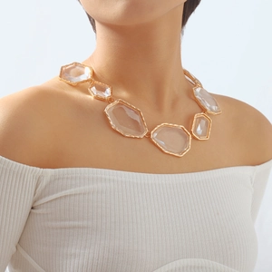 Detail of chunky gold alloy necklace with large transparent resin geometric pendants on model