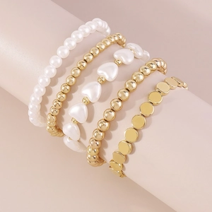 Detalle del conjunto de cinco pulseras minimalistas con perlas y cuentas doradas